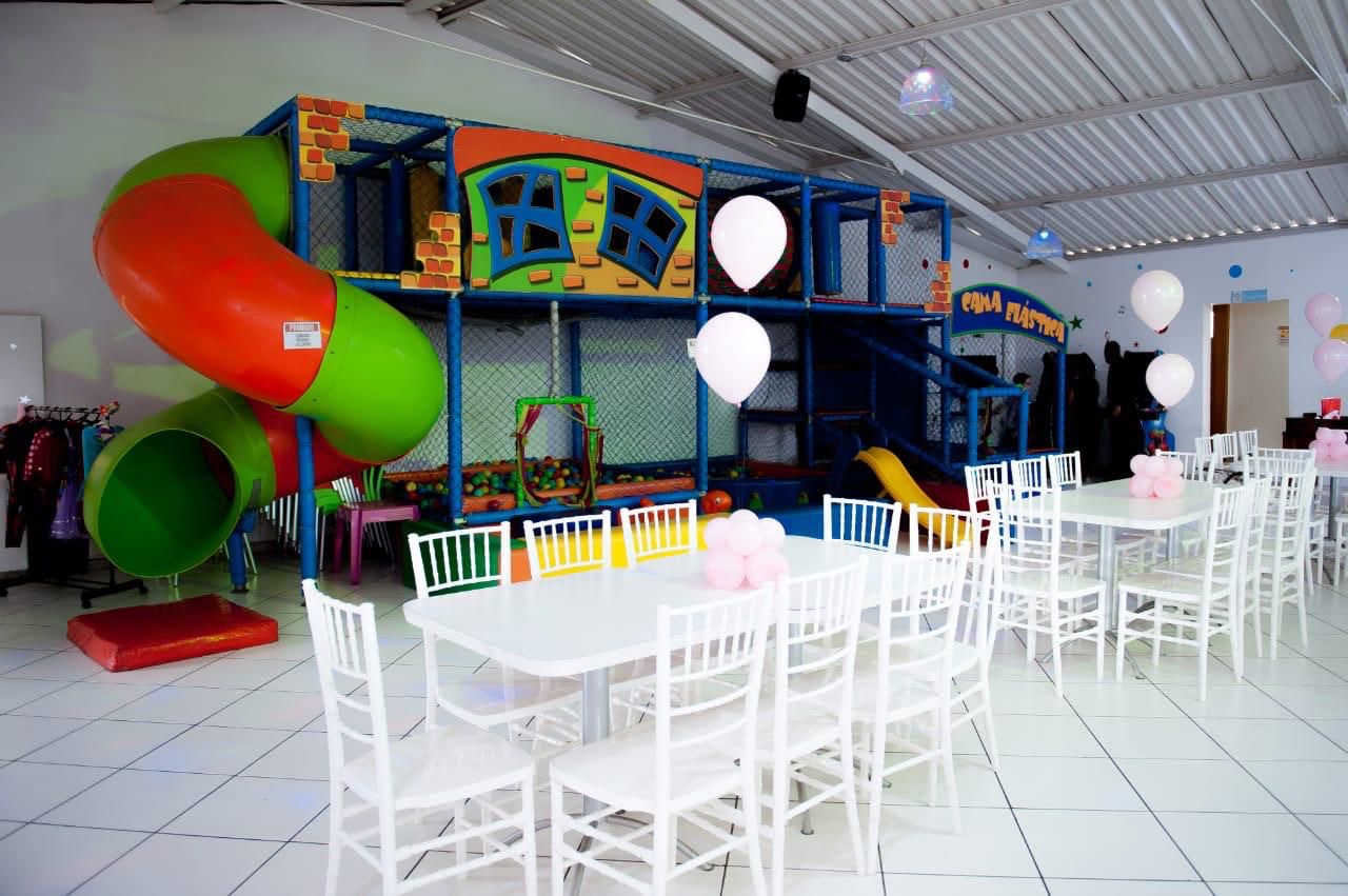 Salão de festas do Tralala montado com mesas, cadeiras e brinquedão